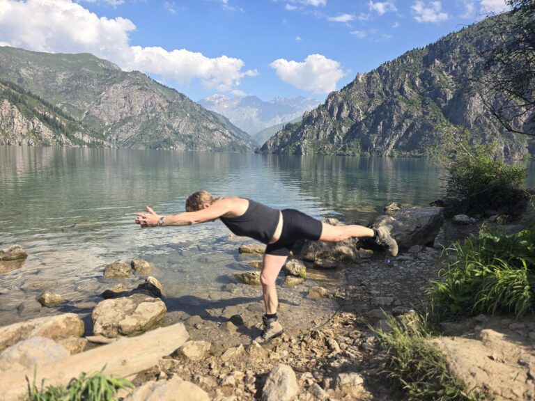 A woman doing a yoga pose on a rock at Sary Chelek Kyrgyzstan.